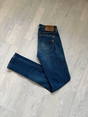 Mörkblå skinny jeans från Dondup - Snygga mörkblå skinny jeans från Dondup med klassisk femficksdesign och läderpatch bak i midjan. Jeansen har en lätt tvättad look och smal passform som sitter tajt längs benen. Perfekta till en avslappnad och trendig stil.