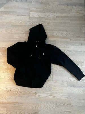 Svart Ralph Lauren Polo Zip Hoodie - Säljer nu en svart Ralph Lauren Polo zip hoodie  Skick 9,5/10 Nytt pris= 2395kr Vårt pris=699kr  Skriv vid minsta fundering!