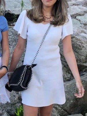 Vit ribstickad kortklänning  - Söt vit kortklänning med v-ringad hals och korta, fladdriga ärmar. Den är lätt ribbad. Köpt på veromoda, använd 1 gång endast och säljs inte längre💓