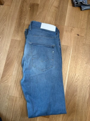 Blå jeans från Replay - REPLAY jeans sitter slim (anbass/grover) Snygga blå jeans från Replay med klassisk femficksdesign och diskret logga på bakfickan. Jeansen har en rak passform och är tillverkade i mjukt denimtyg som ger en avslappnad look. Perfekta för dig som gillar stilrena och tidlösa jeans.