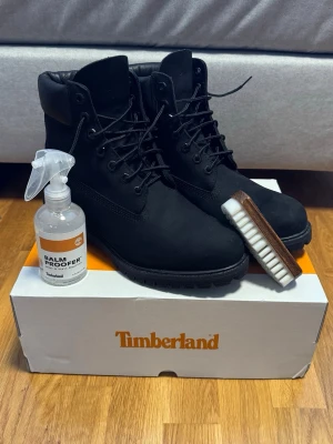 NYA Timberland Premium 6 inch, svarta - Säljer ett par helt nya svarta Timberland Premium 6 inch kängor i nubuck med grov sula och snörning. Dessutom ingår Timberland Balm Proofer (impregnering) och nubuckborste värde 300kr. Timberland garanterar vattentätt material. Riktigt snygga och sköna under vinter/höst/vår.  Storlek 44. Säljer pga fel storlek. Nypris totalt 2699kr – mitt pris 1799kr!