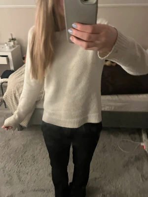 Vit stickad tröja  - Klassisk vit stickad tröja med rund hals och långa ärmar. Tröjan har ribbstickade muddar vid ärmslut och nederkant, vilket ger en enkel men stilren look. Perfekt att matcha med jeans eller kjol för en avslappnad stil.