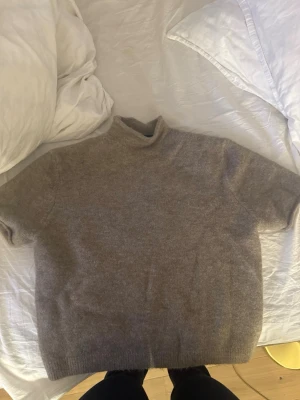 Beige stickad tröja med kort ärm - Mysig beige stickad tröja med korta ärmar och hög hals. Nytt skick med prislapp! Storlek XL men sitter som en S då jag antar att den är väldigt liten i modellen. Skriv i chatten för bild!❤️