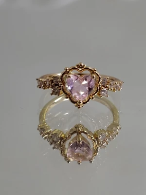 Guldfärgad ring med hjärtformad sten - Guldfärgad ring med rosa kristall hjärta i storlek: 18,1mm (i diameter) eller 56,8mm (i omkrets)