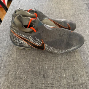 NIKE PHANTOM VISION ELITE DF FG VICTORY - Jag säljer ett par Nike Phantom Vision Elite DF FG Victory. Skorna har använts enstaka gånger och är överlag i bra skick med en mindre kosmetisk defekt: ett litet hål i ovandelen. Trots denna lilla skada är de fullt fungerande och passar perfekt för träning eller samlare som vill ha en autentisk modell. Pris 349, pris kan diskuteras vid snabb affär Storlek 46 