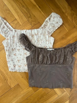 Blommiga toppar med volang - Supersöta blommiga offshoulder toppar i ljus färg med volangdetaljer och kort ärm. Tunt, luftigt material som känns perfekt för varmare dagar. Topparna har små blommor i beige och brunt och en romantisk vibe. Köpta i Kalifornien i USA på Tillys. 1 för 250kr, 2 för 400kr