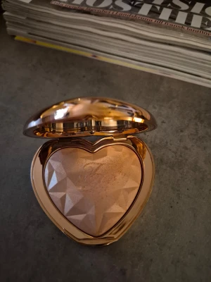 Too Faced hjärtformad highlighter - Highlighter i en lyxig, hjärtformad ask i roséguld från Too Faced. Pudret har en skimrande champagnefärg och en facettslipad yta som ger extra glow till kindbenen. Perfekt för att framhäva ansiktets drag och skapa en strålande finish. Testad, otroligt glow, lyxig förpaxning! Testad produkt. 