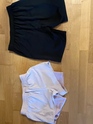 2-pack shorts från H&M, svart & ljusrosa - Två par shorts från H&M, ett par svarta och ett par ljusrosa. Båda har elastisk midja och är tillverkade i mjukt syntetmaterial, perfekta  för träning eller chill. Lätta och bekväma med enkel design. Btw de svarta är inte från hm och ursäkta för suddiga bilder på storleken 