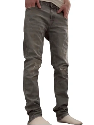Grå slitna jeans från replay - Säljer ett par grå jeans med slim fit och slitningar vid knäna. Jeansen har dragkedjedetaljer ovanför knäna och klassisk femficksdesign. Perfekta för en avslappnad och trendig look. Jeansen är i nytt skick och köpte för inte särskilt länge sedan. Mer bilder eller mått fås på begäran. BVSA mvh//Hugo😊