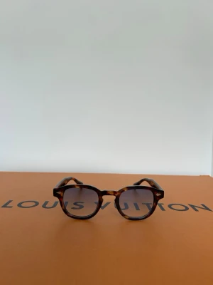 Solglasögon med ljusblått glas  - Snygga och trendiga bruna solglasögon med en klassisk form. De har blåa linser och en stilren design som passar perfekt för soliga dagar. En tidlös accessoar för den modemedvetna. Skicka 10/10. Priset är inte hugget i sten så skicka prisförslag✅ Skriv vid frågor eller funderingar i DM🍾