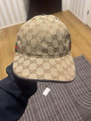 beige GG keps - Säljer en beige keps från G**. Perfekt för dig som gillar exklusiva accessoarer. Storlek M men passar S. Har använt några gånger