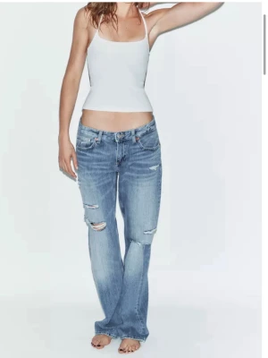 Low waist jeans från Zara - Säljer ett par ljusblå jeans med raka ben och snygga slitningar på låren och knäna. Stolek 40, men skulle säga att den är småby stoleken! Så passar för en med 38 i storlek. Aldrig använda!! Ny pris 399🩷