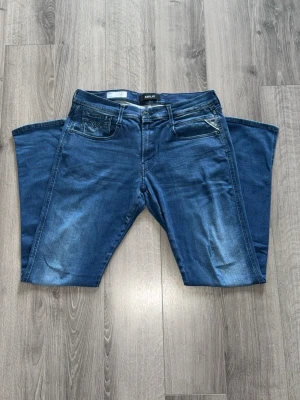 Blå jeans från Replay - Snygga blå jeans från Replay med klassisk femficksdesign och diskreta slitningar framtill. Jeansen har raka ben och normal midja. Materialet är mjukt denim som ger en bekväm känsla och cool look.