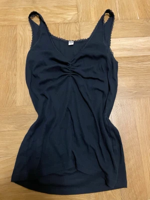 Linne från Uniqlo - Säljer ett marinblått ribbat linne från Uniqlo med spetsdetaljer längs kanterna och v-ringning. Själv sytt till i mitten så det blev ribbat❤️