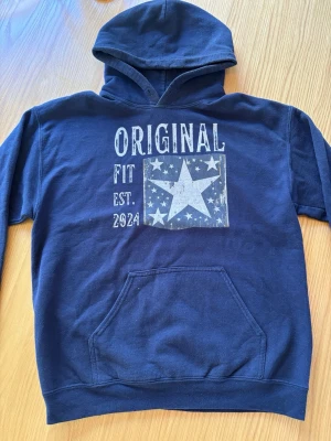 Mörkblå hoodie - Mörkblå hoodie med luva. Jag köpte den på SCNDI för något år sedan när dessa fortfarande såldes. Den är sparsamt använd och jag säljer på grund av att den är för liten. Jag har tagit bort snörena i luvan för att det blev snyggare utan enligt mig. Kan tänka mig att gå ner i pris vid snabb affär. Hör av dig om du har frågor!