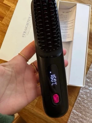 Svart elektrisk hårborste - Säljer en svart elektrisk hårborste med digital display och rosa knapp. Borsten är designad för att platta håret och är portabel, perfekt att ta med sig. Kommer i originalförpackning med instruktioner.
