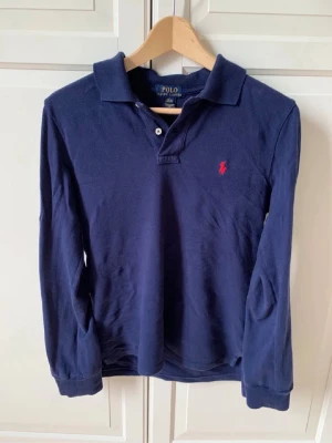 Ralph Lauren pike långärmad - Klassisk marinblå långärmad polotopp från Ralph Lauren med krage och två knappar framtill. 