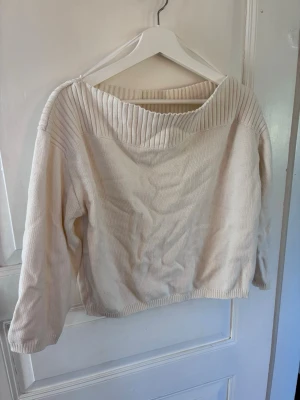 Vit stickad tröja från H&M - Säljer en krämvit stickad tröja från H&M med bred ribbad krage och långa ärmar. Tröjan har en avslappnad passform och är tillverkad i mjukt material, perfekt för lager på lager. Enkel och stilren design som passar till det mesta. Passar snarare S/M.