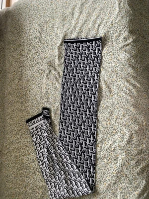 Monogram Halsduk  från Christian Dior - Snygg halsduk från Christian Dior med svartvitt monogrammönster och bred resår i midjan där det står 'CHRISTIAN DIOR'. Stretchigt material som sitter tight och ger en trendig look. Perfekta för dig som vill sticka ut med designerplagg.