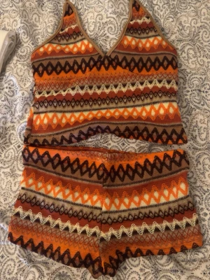 Mönstrat loungewear-set i orange - Säljer ett färgglatt loungewear-set med linne och shorts i stickat material. Setet har ett retroinspirerat mönster i orange, brunt, vitt och svart med vågiga och geometriska detaljer. Perfekt för chill dagar hemma.