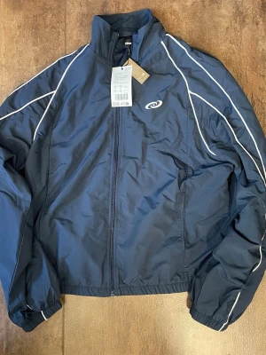 Blå allvädersjacka från YOURTURN - Snygg marinblå allvädersjacka från YOURTURN som aldrig är använd. Den har till och med lappen kvar. Den är av lätt och tåligt material.