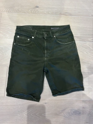 Dondup shorts - Säljer ett par mörkgröna jeansshorts från Dondup med klassisk femficksdesign och knappgylf. Shortsen har normal passform och bälteshällor, samt en liten Dondup på bakfickan. Perfekta för sommaren!
