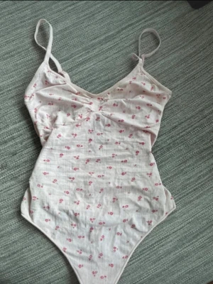 Ljusrosa body med små blommor - Supersöt ljusrosa body med tunna axelband och små rosa blommor. Köpt från New Yorker ny, storlek L men kan passa M också 