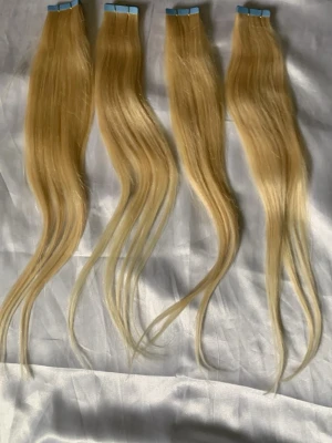 Blonda tape-on löshår slingor 45cm 40 stycken  - Säljer blonda tape-on löshår slingor i en ljus nyans. Slingorna är raka/ vågiga och har en naturlig glans. Fästena är blå och tunna för enkel applicering. Perfekt för dig som vill ha längre eller fylligare hår på ett smidigt sätt.