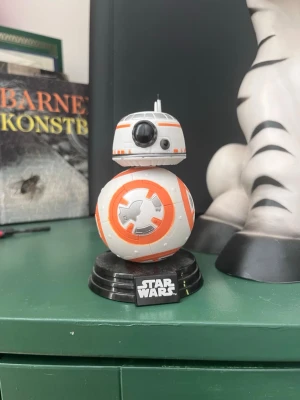 Star Wars BB-8 figur på svart fot - Cool BB-8 figur från Star Wars med vit och orange färg, detaljer i grått och svart. 