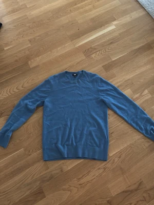 Blå kashmir tröja från Uniqlo - Säljer en stilren blå kashmir tröja från Uniqlo. Tröjan har rund halsringning, långa ärmar och ribbade muddar vid ärmslut och nederkant. Perfekt att bära över en skjorta eller t-shirt för en clean look.