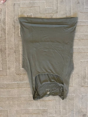 Mörkgrön axelbandslös tubtopp - Snygg mörkgrön tubtopp från 157, helt axelbandslös och i mjukt stretchigt material. Perfekt att styla med jeans eller kjol för en enkel och trendig look.