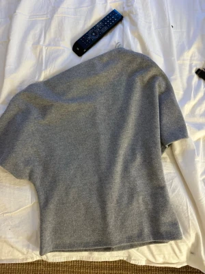Grå stickad topp med kort ärm - Storlek - L, men liten i storleken, mer som en M/S Fint skick - Aldrig använd Nypris - 350 kr Lite snedskuren