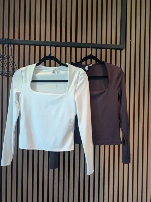 Två långärmade toppar med fyrkantig ringning - Säljer två stilrena långärmade toppar med fyrkantig ringning. En topp är vit och den andra är mörkbrun. Båda är figurnära och har en clean, minimalistisk look som passar till mycket. Perfekta att styla med jeans eller kjol.