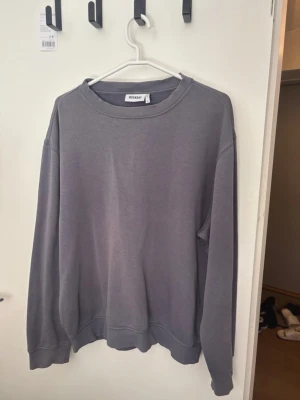 Grå sweatshirt från Weekday - En stilren grå sweatshirt från Weekday med rund halsringning och ribbade muddar vid ärmslut och nederkant. Tröjan har en avslappnad passform och är tillverkad i mjukt bomullsmaterial. Perfekt för en casual look.