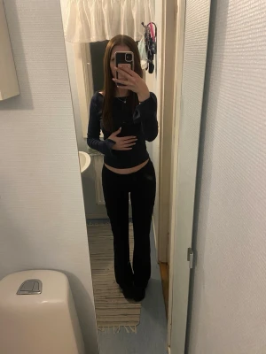 Svarta kostymbyxor med knappar från Gina tricot  - Säljer ett par svarta bootcut byxor med låg midja och två dekorativa knappar framtill. Byxorna har en lätt utsvängd passform och är perfekta för en trendig och bekväm stil. Materialet är stretchigt och mjukt för extra komfort. Från Gina Young i storlek 158, för korta på mig därför säljer jag. (Har på mig en större storlek på första bilden). Byxorna är i nyskick, pris kan diskuteras så skicka gärna prisförslag. 