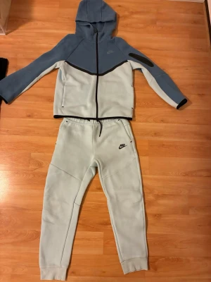 Ljusblå mjukisbyxor från Nike - Snygga ljusblå mjukisbyxor från Nike med svart logga på vänster lår. Byxorna har dragsko i midjan och är tillverkade i mjukt material som passar perfekt för chill eller träning. Matcha med hoodie för en komplett look.