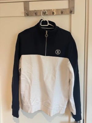 Blåvit half-zip sweatshirt Bondelid - Snygg sweatshirt från Bondelid i blått och vitt med half-zip och ståkrage. Tröjan har en broderad logga på bröstet och är tillverkad i mjukt bomullsmaterial. Perfekt för en avslappnad och sportig stil. Det är snarare S/M även fast det står L.