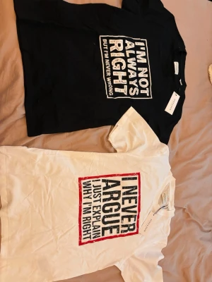 Två grafiska t-shirts med text - Två t-shirts från Zara, en svart med vit text 'I'M NOT ALWAYS RIGHT BUT I'M NEVER WRONG' och en vit med svart och röd text 'I NEVER ARGUE JUST EXPLAIN WHY I'M RIGHT'. Båda har klassisk passform och rund hals.