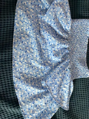 Blommig blå kortkjol från UNIQ YOUNG - Söt blå kortkjol från UNIQ YOUNG med små vita och blå blommor. Kjolen har smock i midjan för en bekväm passform och är gjord i ett lätt material som passar perfekt till varmare dagar. Den har en volangdetalj som ger extra rörelse och stil.❤️❤️❤️