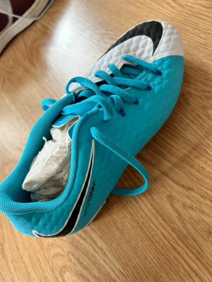 Nike Hypervenom blå fotbollsskor - Säljer ett par Nike Hypervenom fotbollsskor i blått med vita och svarta detaljer. Skon har snörning, låg profil och är tillverkad i syntetmaterial för bra bollkontroll. Perfekt för dig som vill sticka ut på planen med stilrena färger och grym passform. Skriv gärna vid funderingar mvh! 36,5 är storleken btw