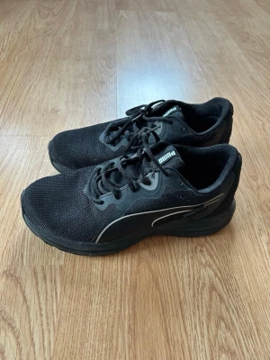 Svarta Puma sneakers med mesh - Snygga svarta sneakers från Puma med ovandel i mesh och syntetdetaljer. Skorna har klassisk låg profil, svarta skosnören. Perfekta för en sportig och stilren look. Skriv vid funderingar! mvh!! Storleken är 37. 