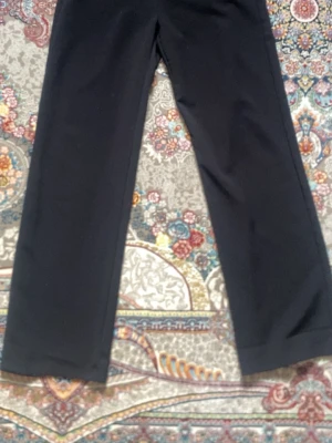 Svarta vida kostymbyxor - Snygga svarta kostymbyxor med rak och vid passform. Byxorna har klassisk design utan synliga detaljer och är perfekta för en clean och stilren look. Materialet ser ut att vara mjukt och följsamt, vilket ger en skön känsla.