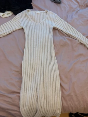 Långärmad ribbad klänning H&M - Långärmad, ribbad klänning från H&M i ljusbeige färg. Klänningen har v-ringning och är stickad i ett mjukt material som ger en skön och slim passform. Perfekt för dig som gillar en enkel men snygg look.