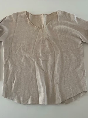 Beige loose topp med v-ringning - Enkel och stilren beige topp med v-ringning och loose passform. Toppen är ärmlös och tillverkad i ett mjukt material som känns skönt mot huden. Perfekt att matcha med jeans eller kjol för en avslappnad look. Storlek ONESIZE passar mig som xs