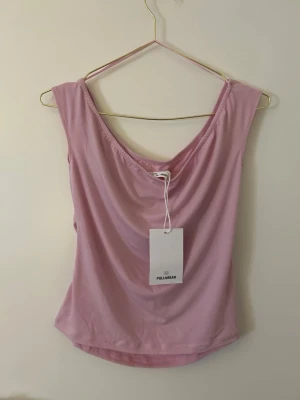 Ljusrosa linnetopp från Pull&Bear - Söt ljusrosa linnetopp från Pull&Bear med djup urringning och mjukt, stretchigt material. Toppen är ärmlös och har en enkel, stilren design som passar perfekt till jeans eller kjol.