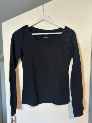Svart långärmad topp  - En enkel och stilren svart långärmad topp med rund halsringning. Perfekt att matcha med jeans eller kjol. Materialet är mjukt och stretchigt bomull som ger en bekväm passform. Passar dig som gillar minimalistisk stil.