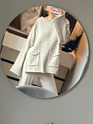 Beige oversized stickad tröja - Beige stickad tröja i oversized modell med två stora fickor framtill och slitsar i sidorna. Vida ärmar och avslappnad passform ger en chill vibe. Materialet ser mjukt och mysigt ut, perfekt för lager-på-lager.