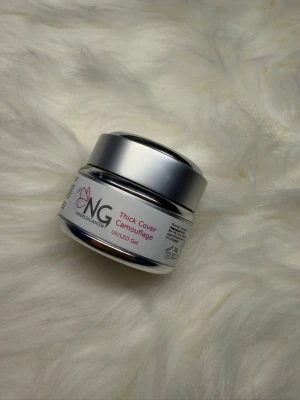 NG Thick Cover Camouflage UV/LED Gel - NG Thick Cover Camouflage är en UV/LED gel för naglar, perfekt för att bygga och forma naglar med ett naturligt resultat. Kommer i en rund burk med silverlock. Gelen har en kamouflagefärg som smälter in snyggt med nagelbädden.