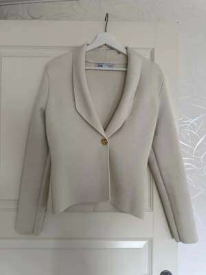 Krämvit kavaj från Zara - Stilren krämvit kavaj från Zara med en knapp framtill i guld. Storlek M men jag tycker stt den  passar mer till S