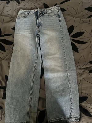 Loose fit jeans från H&M ljusblå - Säljer ett par loose fit jeans från H&M i ljusblå tvätt med justerbar midja. Jeansen har raka ben och klassisk femficksdesign. Perfekta för en avslappnad och trendig look. Materialet är bomull med slitstark känsla.